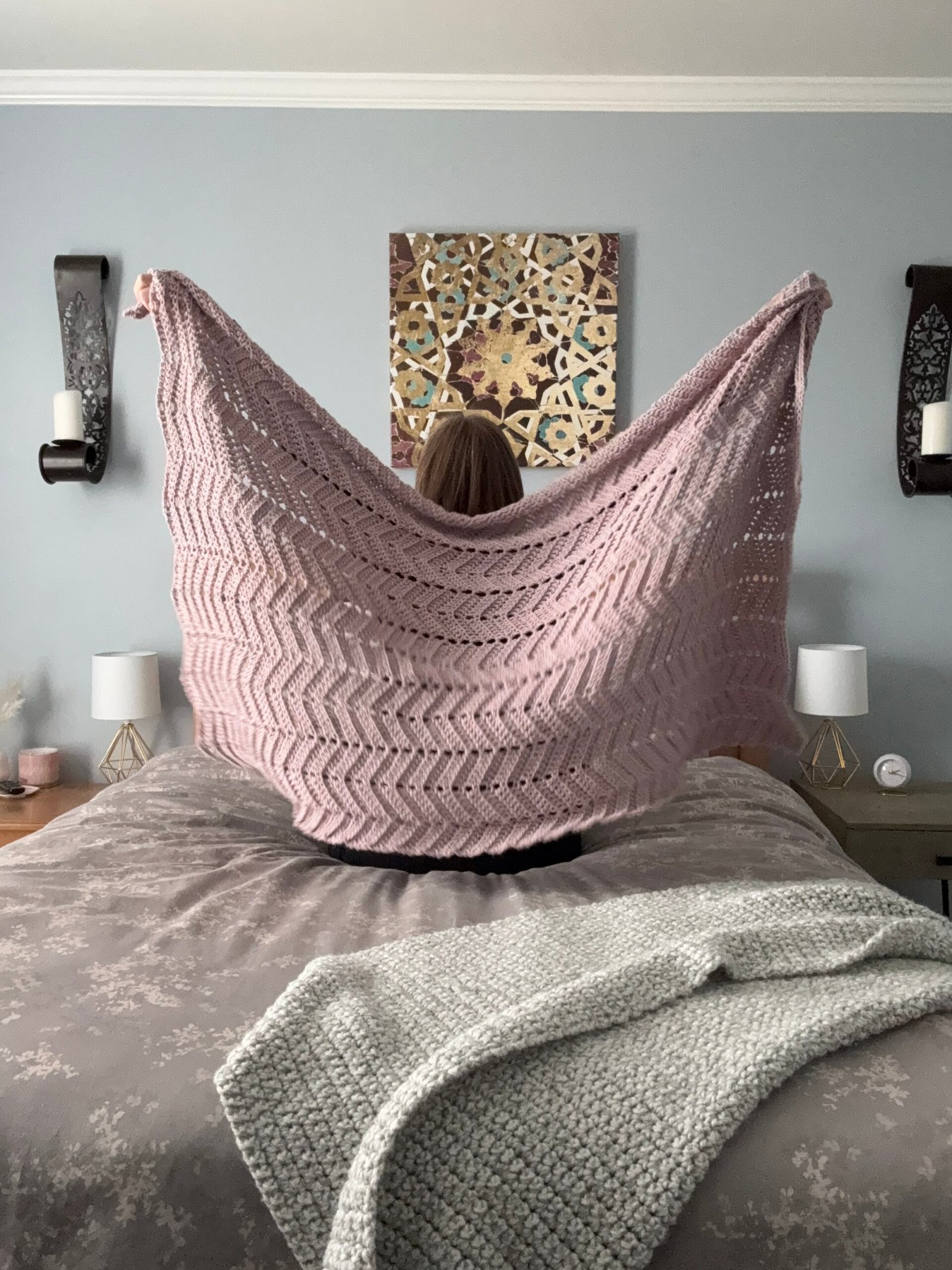 Kate, owner of Beets & Stitches, sitting on bed with crochet blanket