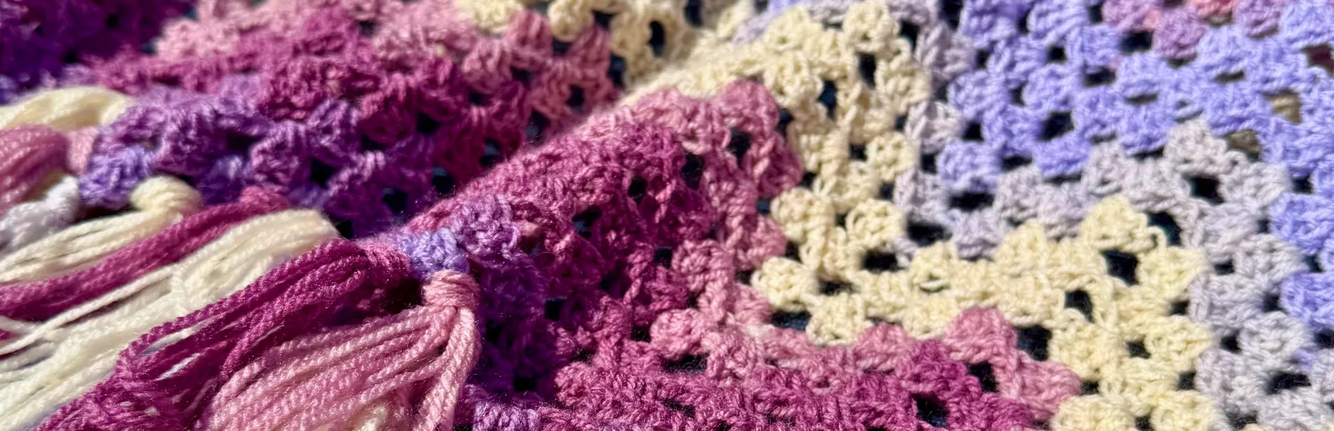 chevron pattern crochet blanket in cream and purple with tassels
