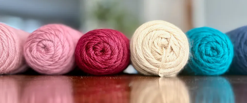 six skeins of yarn in various colors on a table